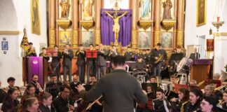 Banda de Música Las Golondrinas durante un concierto en una iglesia, con su director de espaldas